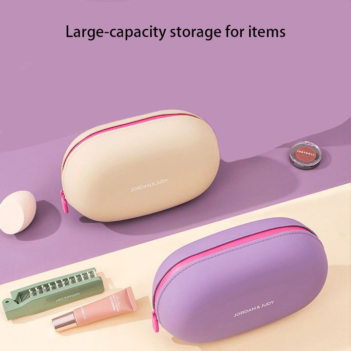 Minimalist pebble-shaped silicone makeup pouches in sage green, lavender, and cream, displayed on aesthetic white blocks for modern travel organization.
