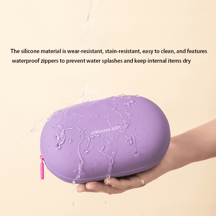 Minimalist pebble-shaped silicone makeup pouches in sage green, lavender, and cream, displayed on aesthetic white blocks for modern travel organization.